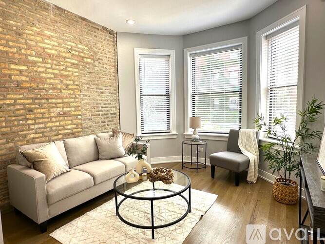 A living room with a white couch, a glass coffee table, and a brick wall.