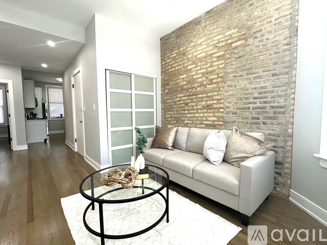 A living room with a white couch and a brick wall.