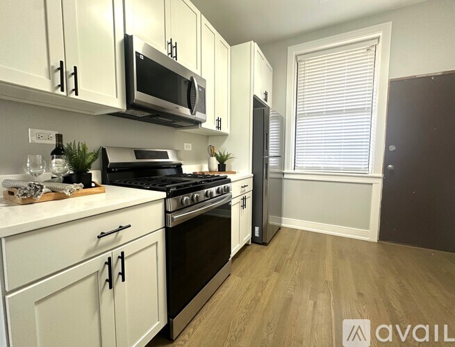 A kitchen with white cabinets and a black microwave.