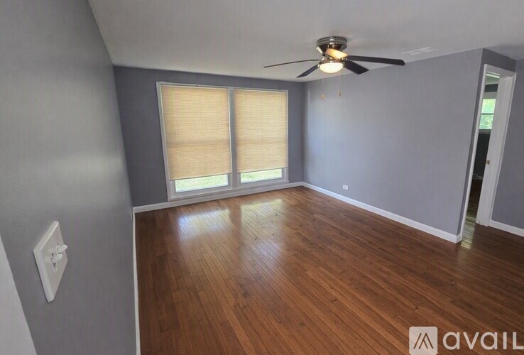 A room with wooden flooring and a ceiling fan.