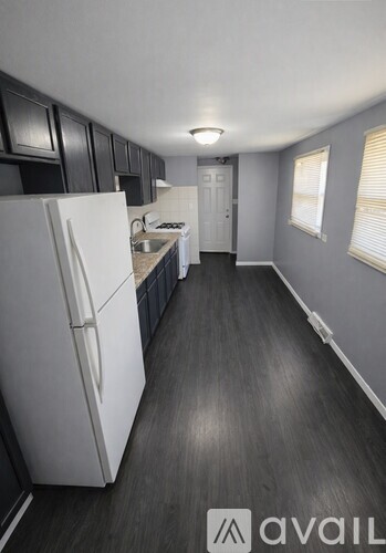 A kitchen with a white fridge and black cabinets.