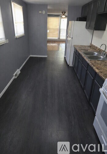 A kitchen with black cabinets and a white fridge.