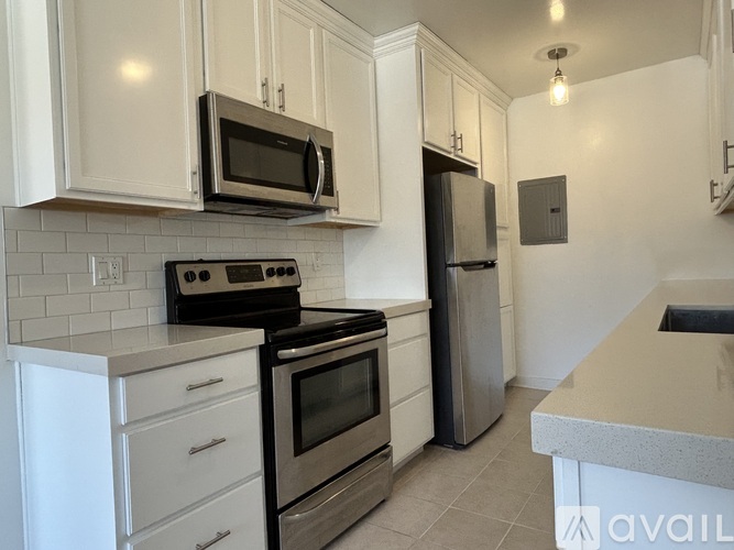 A kitchen with white cabinets and black appliances.