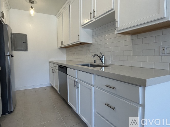 A kitchen with white cabinets and a grey backsplash.