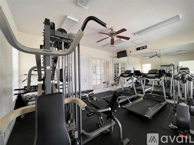 A gym with treadmills, elliptical machines, and a fan.
