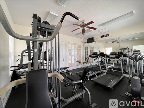 A gym with treadmills, elliptical machines, and a fan.
