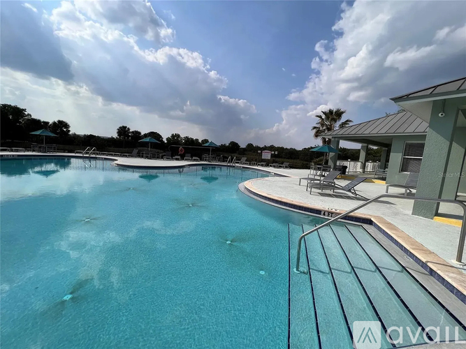 A large outdoor swimming pool with a metal railing and a building in the background.