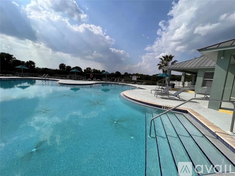 A large outdoor swimming pool with a metal railing and a building in the background.