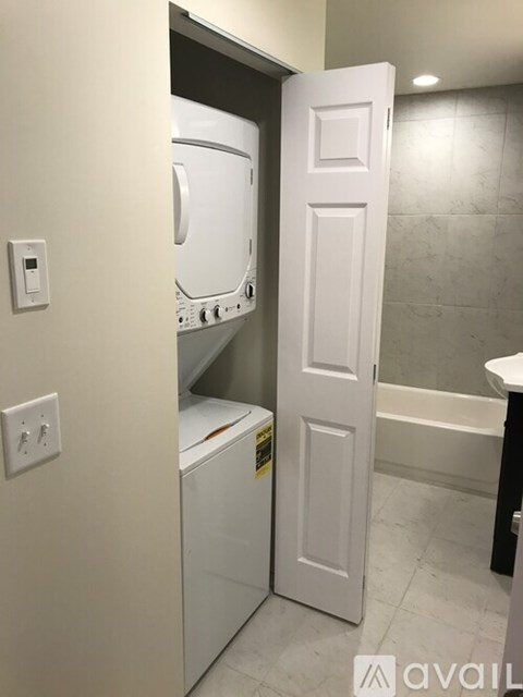 A white door is open to a bathroom with a washer and dryer in it.