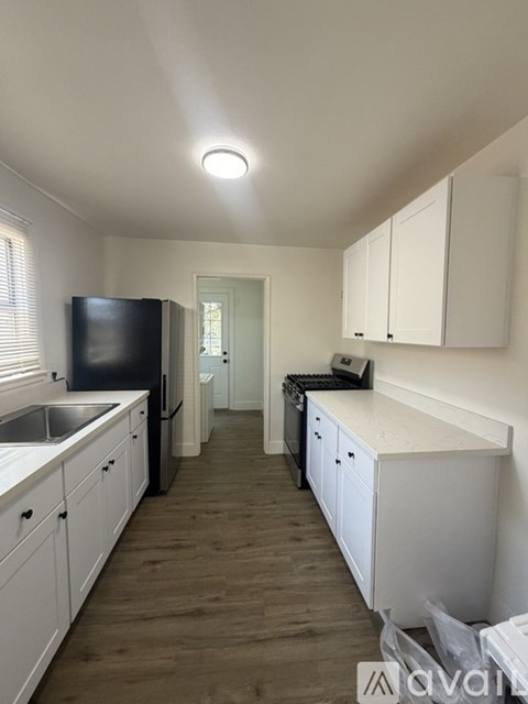 A kitchen with white cabinets and a black fridge.