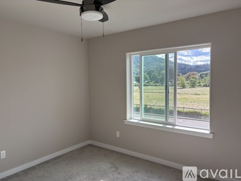 A room with a ceiling fan and a window showing a view of the outdoors.