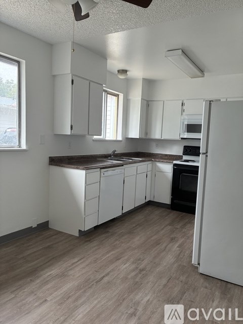 A kitchen with white cabinets and a wooden floor.