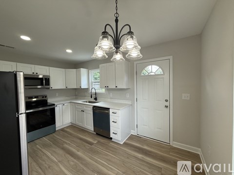 A kitchen with a black refrigerator and white cabinets.