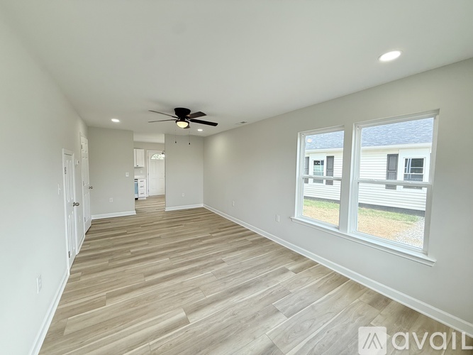 A spacious room with a ceiling fan and wooden flooring.