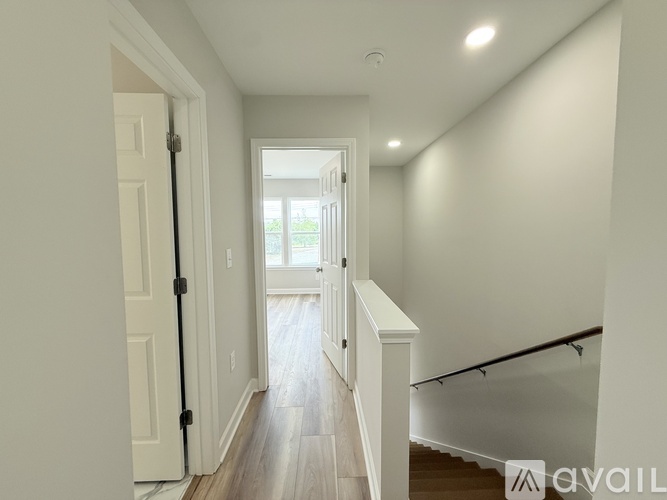 A hallway with a white door and a window with a view of trees outside.
