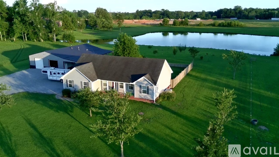A house with a large lawn and a pond in the background.