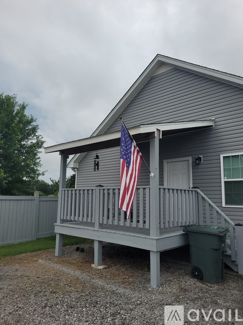 A house with a grey roof and a grey porch with a flag on it.