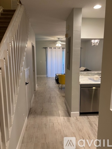 A hallway with a staircase on the left and a bedroom on the right.