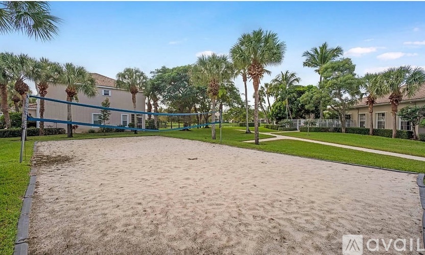 A sandy area with palm trees and a building in the background.