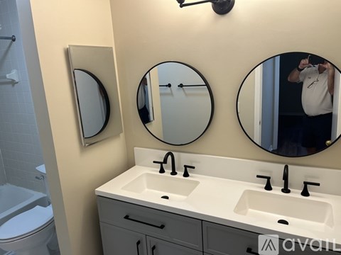 A bathroom with a sink, mirror and a man taking a picture.