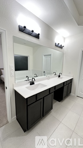 A bathroom with a white sink and black cabinets.