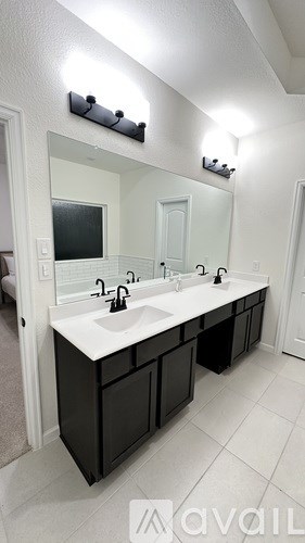 A bathroom with a white sink and black cabinets.