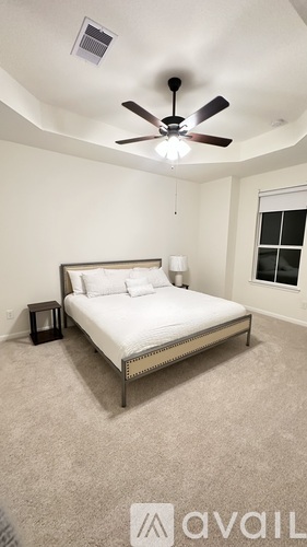 A bedroom with a bed, a ceiling fan, and a nightstand.
