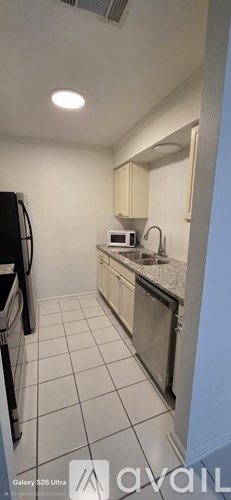 A kitchen with white cabinets and a black refrigerator.