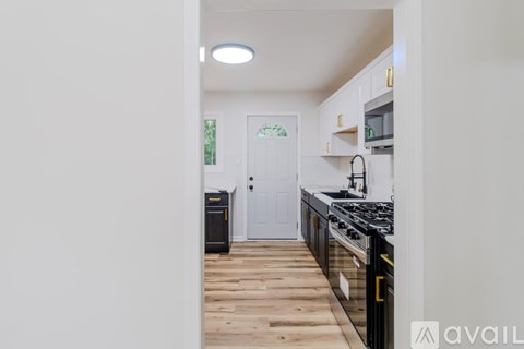 A kitchen with a black stove top oven and wooden flooring.