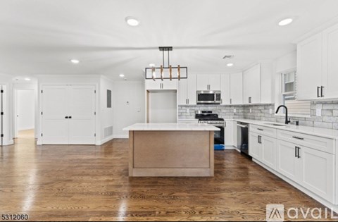 A kitchen with white cabinets and a wooden island.