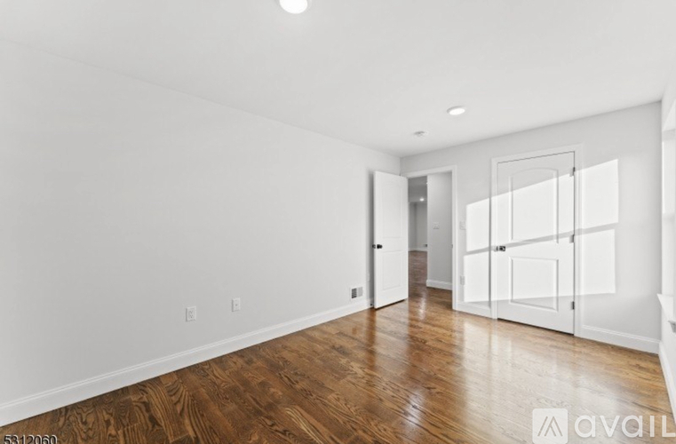 A spacious room with wooden floors and white walls.