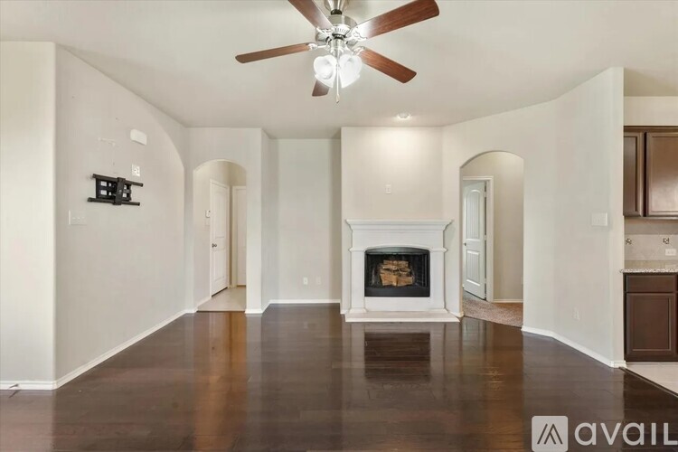 A spacious living room with a fireplace and a ceiling fan.
