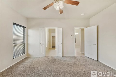 A spacious room with a ceiling fan and carpeted floor.