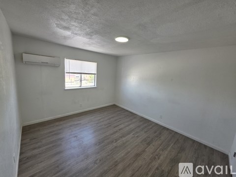 A room with wooden flooring and a window with blinds.