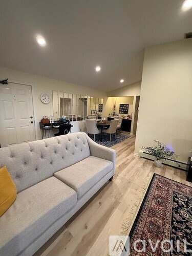 A living room with a grey tufted couch and a rug.