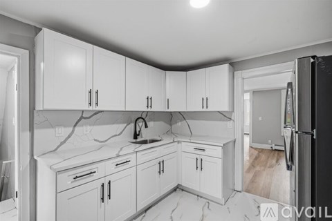A kitchen with white cabinets and a black refrigerator.