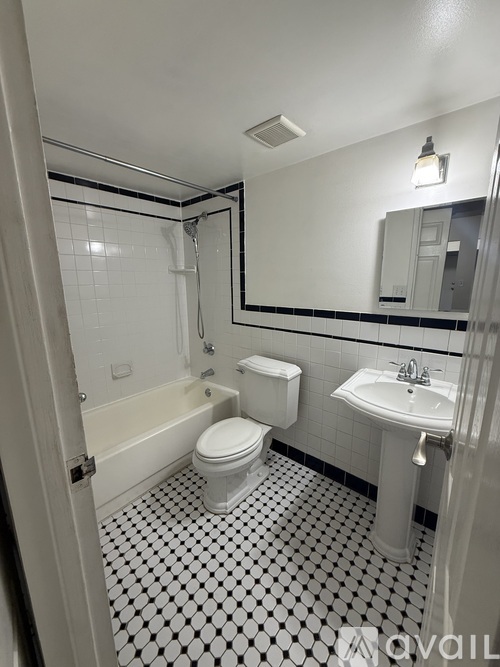 A white toilet sits in a bathroom with a black and white tiled floor.
