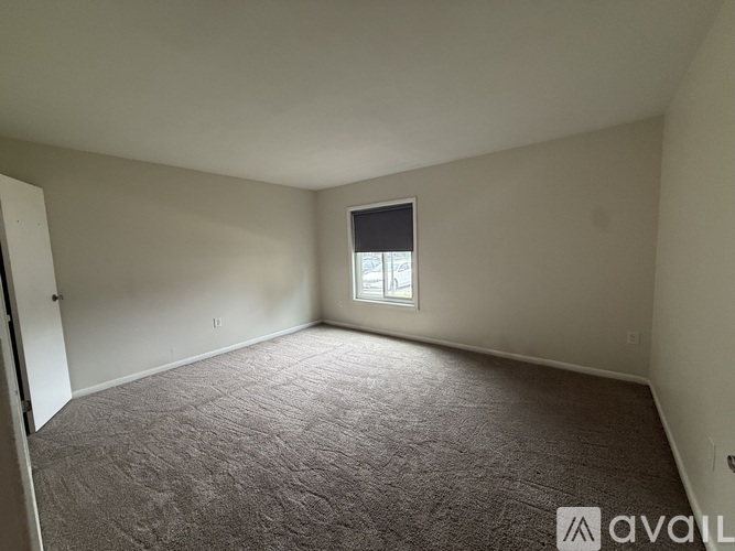 A carpeted room with a window and a door.