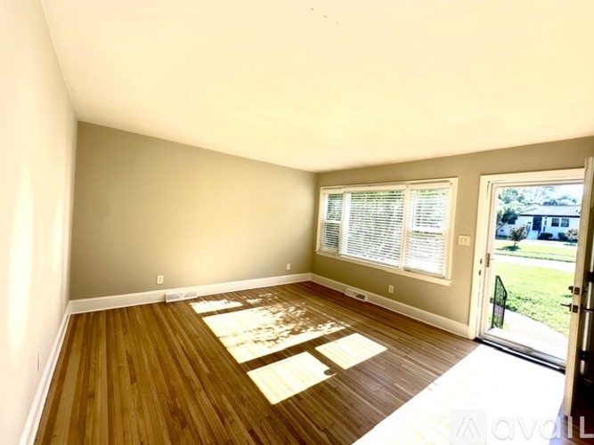 A room with wooden floors and a window with blinds.