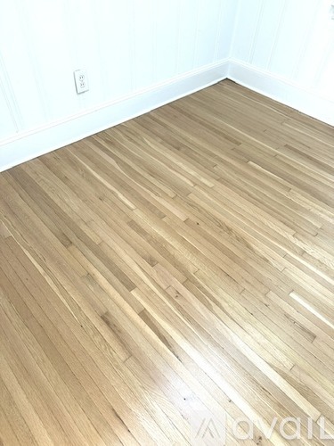 A room with a light wood floor and a white wall.