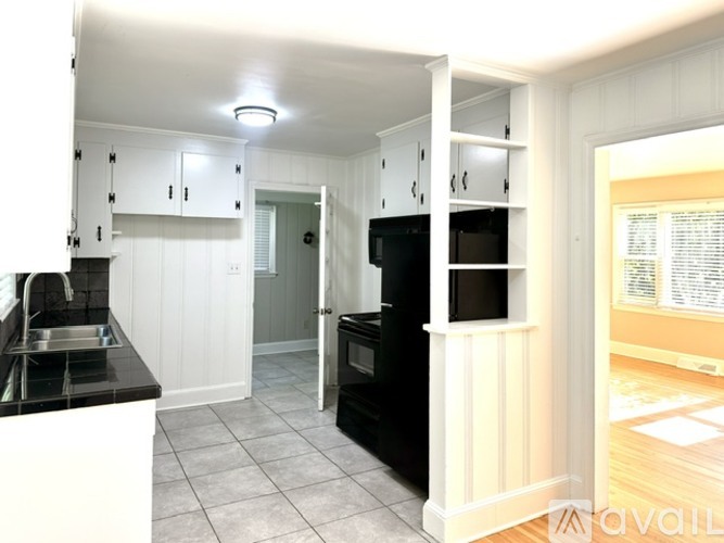 A kitchen with white cabinets and black appliances.