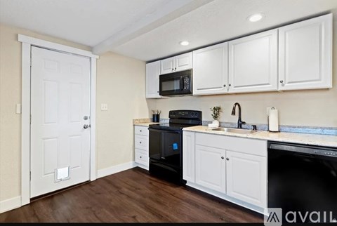 A kitchen with white cabinets and a black dishwasher.