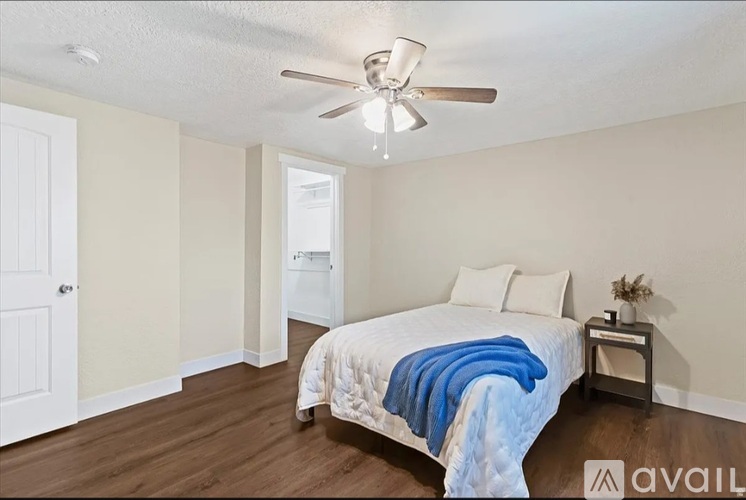 A bedroom with a bed, a ceiling fan, and a nightstand.