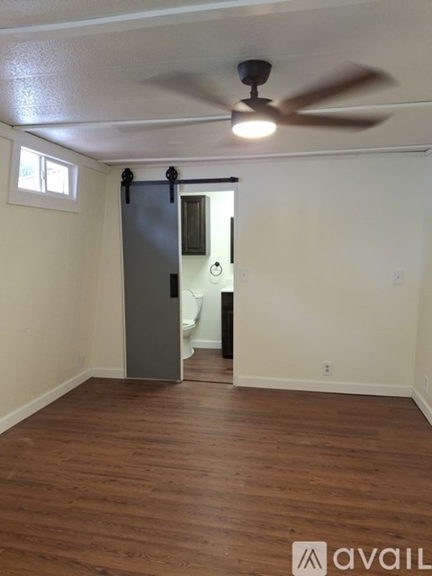 A room with a ceiling fan and a door leading to a bathroom.