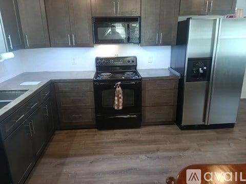 A kitchen with a black stove top oven and a black refrigerator.