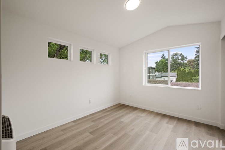 A room with a window showing a view of a house and trees.