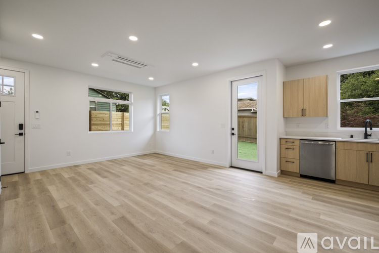 A spacious room with wooden flooring and a kitchen area with a sink and cabinets.