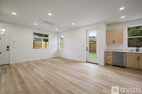 A spacious room with wooden flooring and a kitchen area with a sink and cabinets.