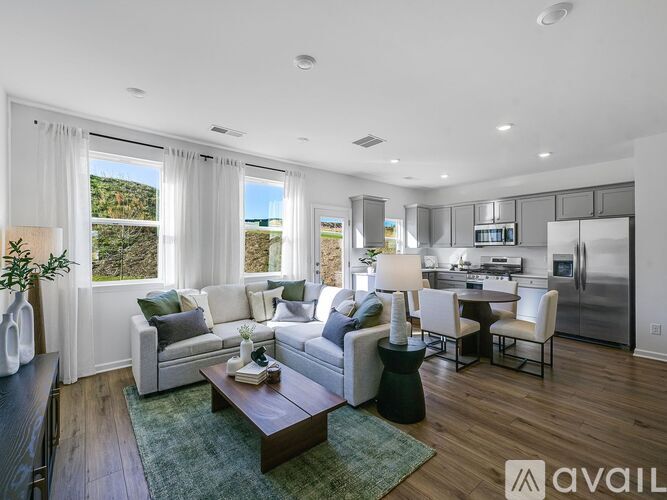 A modern living room with a kitchen in the background.