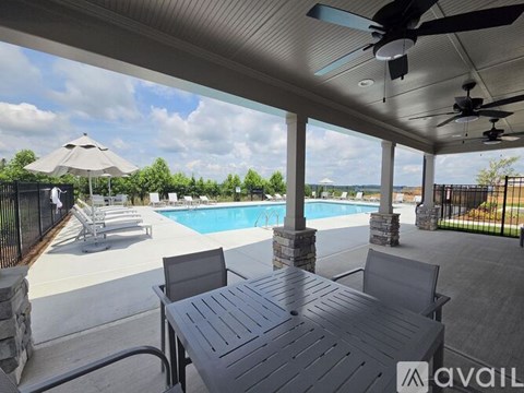 A patio with a table and chairs overlooking a pool.